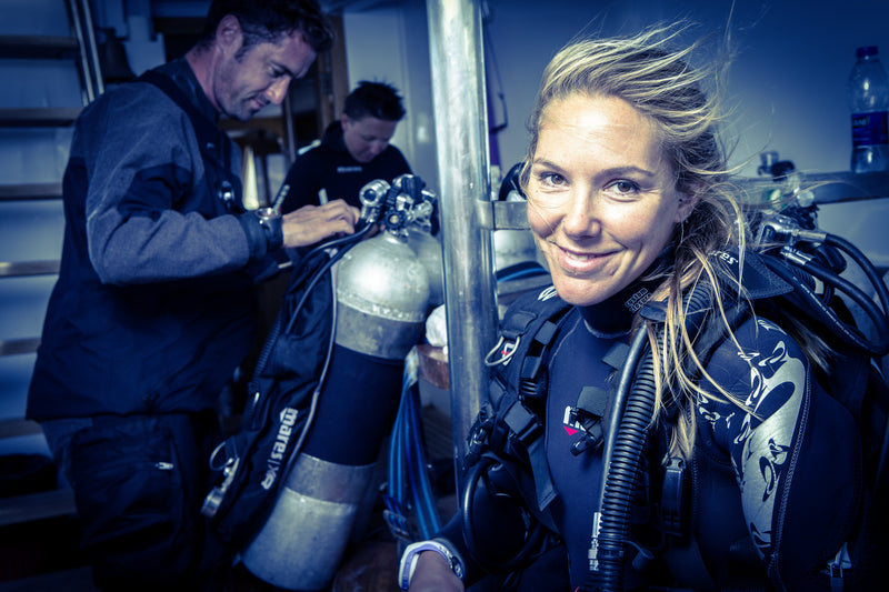 Divers preparing their equipment while wearing exposure suits
